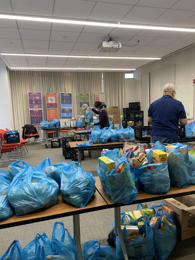 Three volunteers bagging food at an APAH grocery distribution 