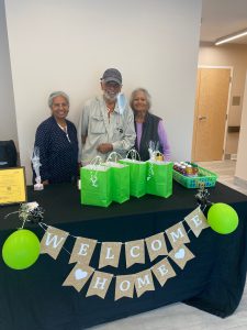 New residents at Loudoun View Senior stand smiling behind a table that says "Welcome Home"